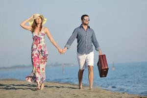 casal na praia com mala de viagem foto