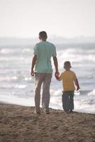 pai e filho caminhando na praia foto