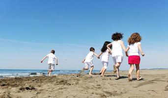 grupo criança feliz jogando na praia foto