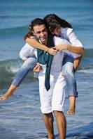 feliz casal jovem se diverte na bela praia foto