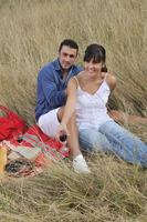 casal feliz desfrutando de piquenique no campo em grama longa foto