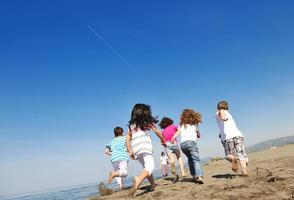 grupo criança feliz jogando na praia foto