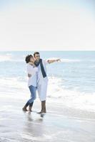 feliz casal jovem se diverte na bela praia foto