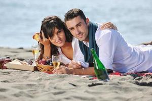 jovem casal desfrutando de piquenique na praia foto