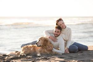 casal com cachorro aproveitando o tempo na praia foto