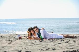 jovem casal desfrutando de piquenique na praia foto