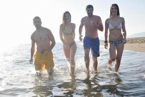 grupo de pessoas felizes se divertir e correr na praia foto