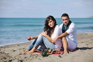 jovem casal desfrutando de piquenique na praia foto