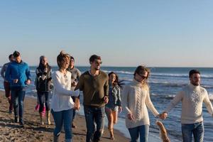 grupo de amigos correndo na praia durante o dia de outono foto
