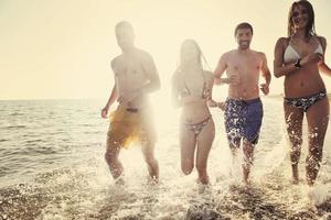 grupo de pessoas felizes se divertir e correr na praia foto