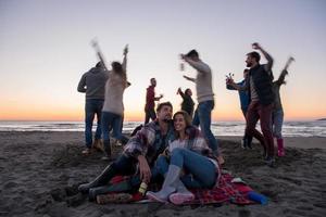 casal curtindo com amigos ao pôr do sol na praia foto