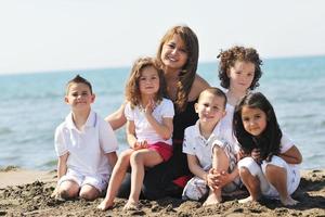 retrato de grupo de crianças com professor na praia foto