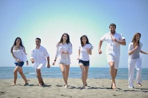 grupo de pessoas felizes se divertir e correr na praia foto