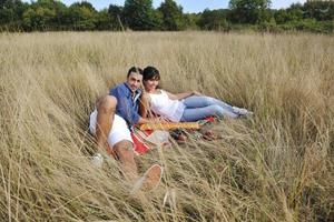 casal feliz desfrutando de piquenique no campo em grama longa foto