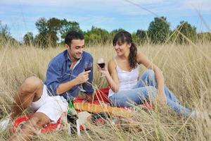 casal feliz desfrutando de piquenique no campo em grama longa foto