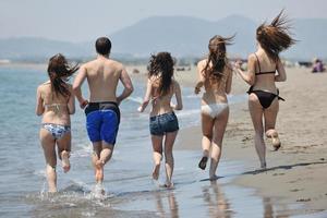 grupo de jovens felizes se divertem na praia foto