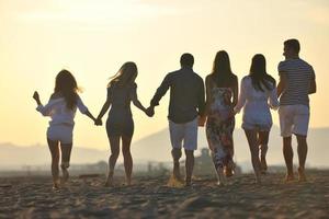 grupo de jovens felizes em se divertir na praia foto