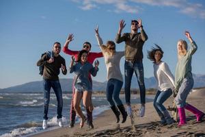 jovens amigos pulando juntos na praia de outono foto