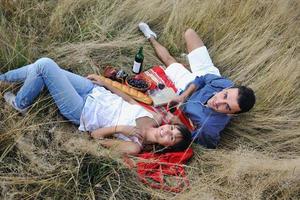 casal feliz desfrutando de piquenique no campo em grama longa foto