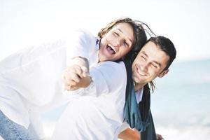 feliz casal jovem se diverte na bela praia foto