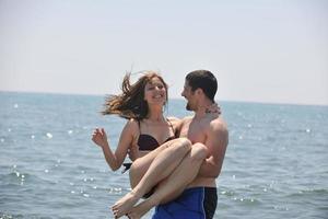 feliz casal jovem se divertir na praia foto