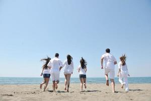 grupo de pessoas felizes se divertir e correr na praia foto