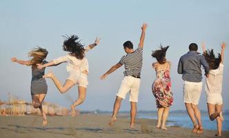 grupo de jovens felizes se divertem na praia foto