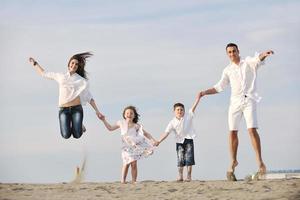 feliz jovem família se divertir na praia foto