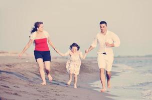 feliz jovem família se divertir na praia foto