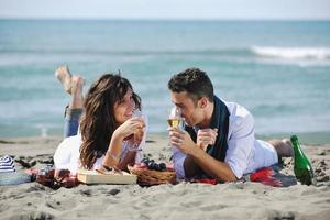 jovem casal desfrutando de piquenique na praia foto