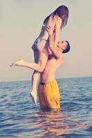 feliz casal jovem se divertir na praia foto