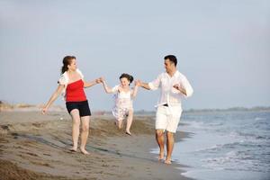 feliz jovem família se divertir na praia foto