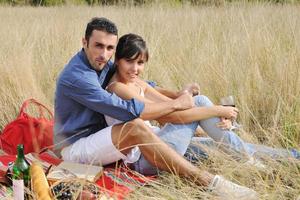 casal feliz desfrutando de piquenique no campo em grama longa foto