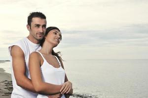 feliz casal jovem se diverte na bela praia foto