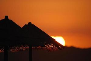 sol na praia com silhueta de guarda-sóis foto