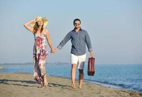 casal na praia com mala de viagem foto