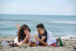 jovem casal desfrutando de piquenique na praia foto