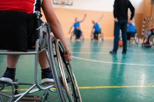 o selecionador do time de basquete com deficiência fica na frente dos jogadores e mostra os exercícios de alongamento antes do início do treinamento foto