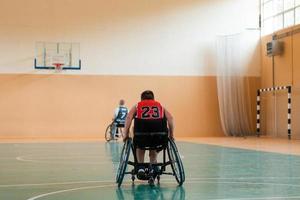 o menino se senta em uma cadeira de rodas e se prepara para o início do jogo de basquete na grande arena foto