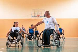 uma equipe de veteranos de guerra em cadeiras de rodas jogando basquete, comemorando pontos ganhos em um jogo. conceito de cinco altos foto