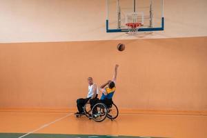 veteranos de guerra com deficiência em ação enquanto jogavam basquete em uma quadra de basquete com equipamentos esportivos profissionais para deficientes foto