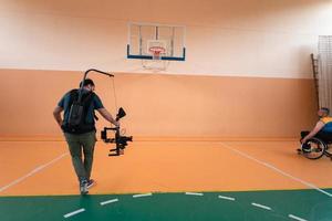 um cinegrafista com equipamento profissional grava uma partida da seleção nacional em cadeira de rodas jogando uma partida na arena foto