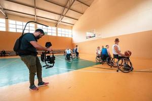 um cinegrafista com equipamento profissional grava uma partida da seleção nacional em cadeira de rodas jogando uma partida na arena foto