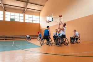 Veteranos de guerra com deficiência equipes de basquete de raça mista e idade em cadeiras de rodas jogando uma partida de treinamento em um ginásio de esportes. conceito de reabilitação e inclusão de pessoas com deficiência foto
