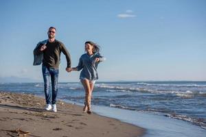 amando o jovem casal em uma praia em dia ensolarado de outono foto