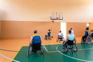 Veteranos de guerra com deficiência equipes de basquete de raça mista e idade em cadeiras de rodas jogando uma partida de treinamento em um ginásio de esportes. conceito de reabilitação e inclusão de pessoas com deficiência foto