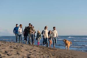 grupo de amigos correndo na praia durante o dia de outono foto