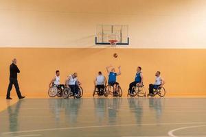 veteranos de guerra com deficiência em ação enquanto jogavam basquete em uma quadra de basquete com equipamentos esportivos profissionais para deficientes foto