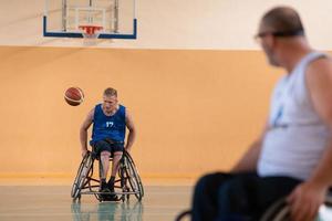 veteranos de guerra deficientes em cadeiras de rodas com equipamento profissional jogam basquete no salão. o conceito de esportes com deficiência foto