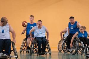 Veteranos de guerra com deficiência, equipes de basquete opostas de raça mista em cadeiras de rodas fotografadas em ação enquanto jogavam uma partida importante em um salão moderno. foto